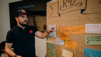 Christopher Siebenhüner, CEO von GECKO.2, steht vor einer Papiertafel mit der Überschrift R42 und unterschiedlichen beschriebenen Karten darunter