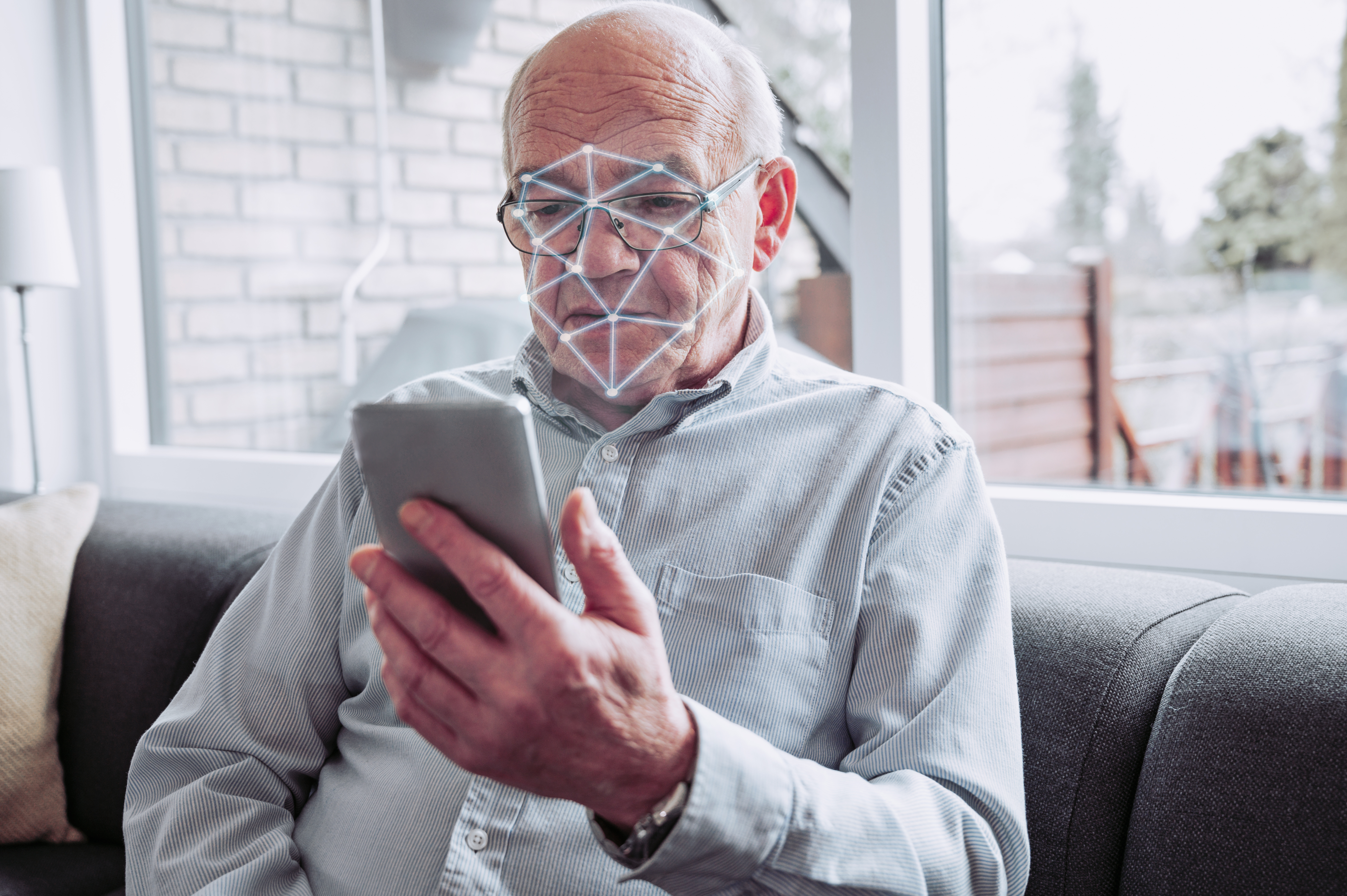 Mann schaut auf Mobiltelefon während das Mobiltelefon sein Gesicht scannt.