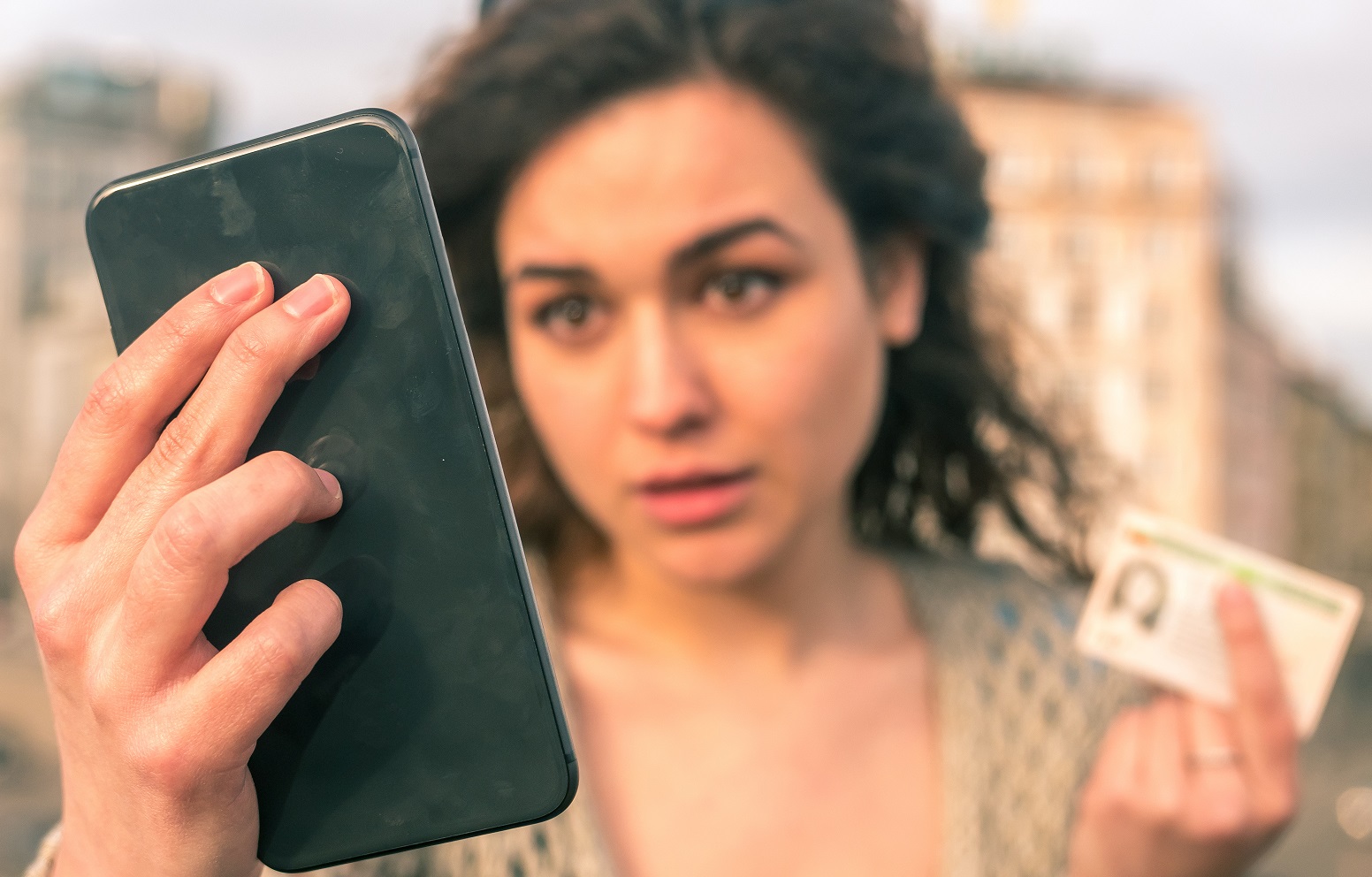 Frau macht Foto mit Mobiltelefon von sich selber mit ihrem Personalausweis in der Hand zur Identifizierung.